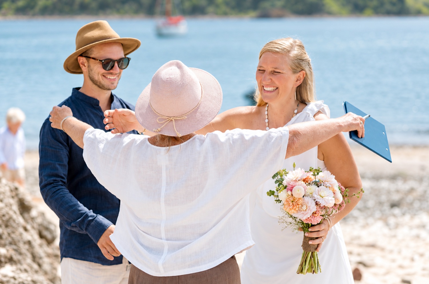 Chris embracing a couple after their beach ceremony